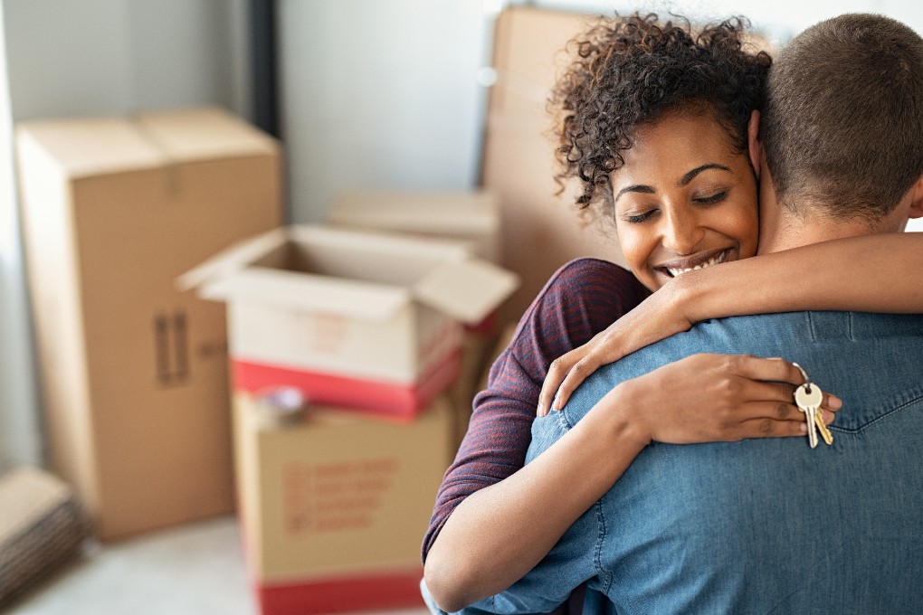 A couple of new homeowners hug after taking possession of their home.