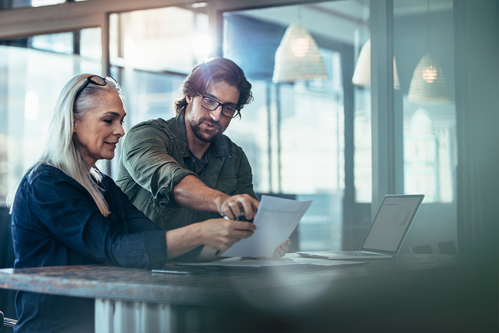 Un homme et une femme dans un bureau regardant un ordinateur portatif.