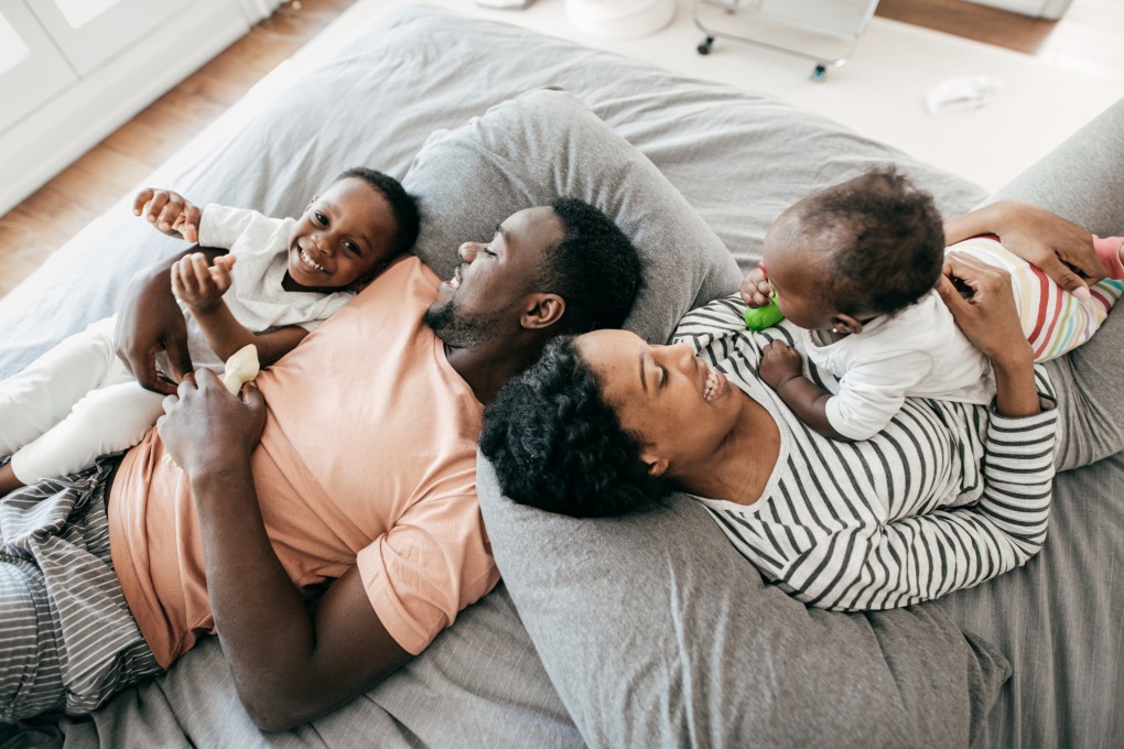 A pregnant woman and her partner play in the living room with their child.