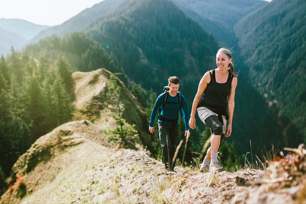 Photo of a woman and a man hiking on top of a mountain 