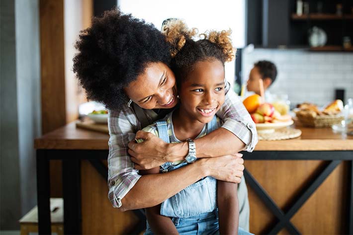 Mother and daughter hugging, head-to-head