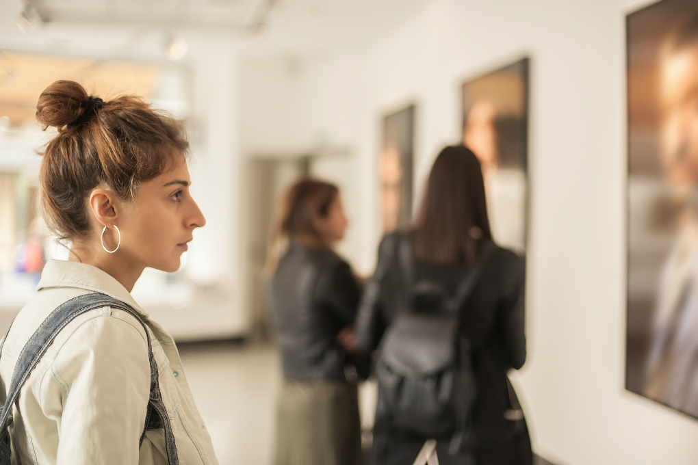 Photo of a woman looking at paintings in an art gallery. 