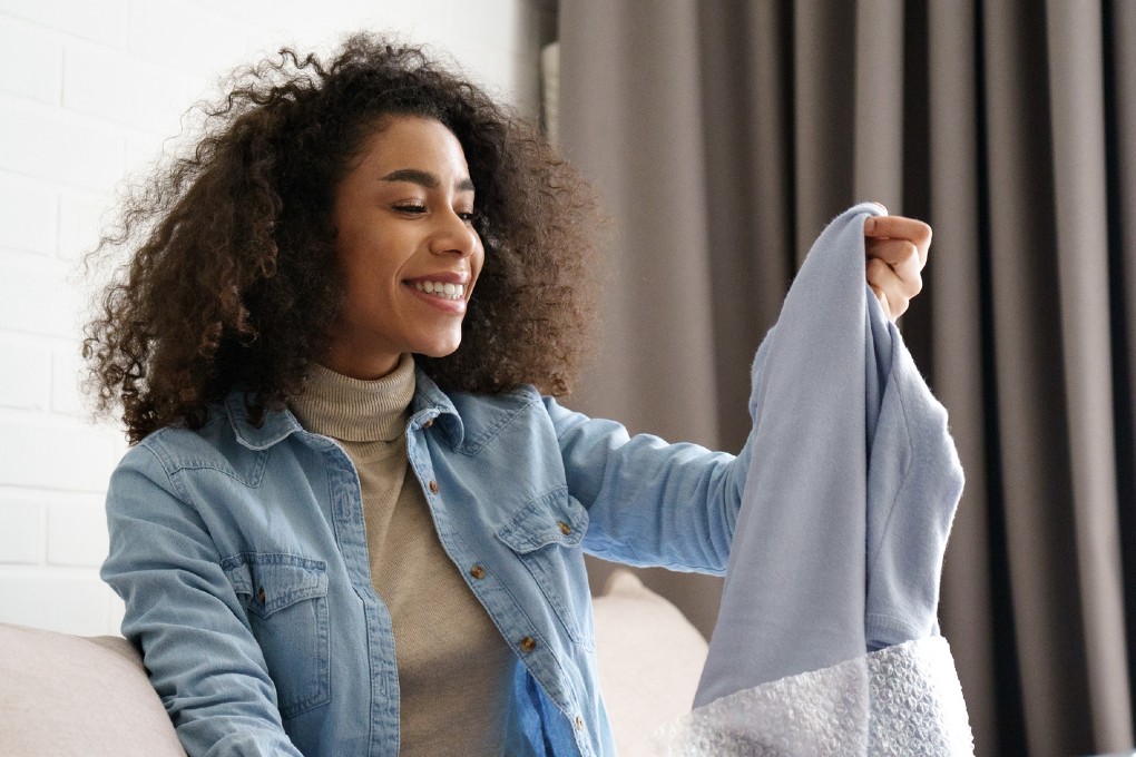 Une femme se réjouit d’avoir enfin reçu le pull qu’elle a commandé par internet et qu’elle paie par versements égaux.