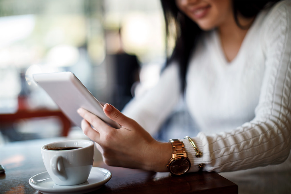 Photo of a sitting woman reading on a tablet