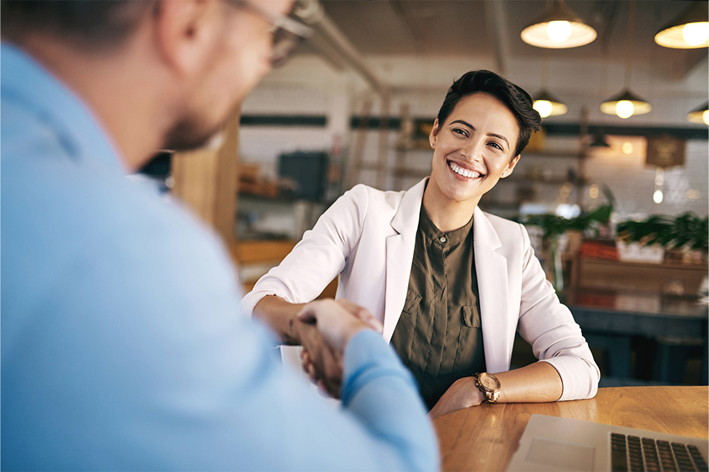 Une femme souriante et assise qui discute avec un homme dans un bureau.