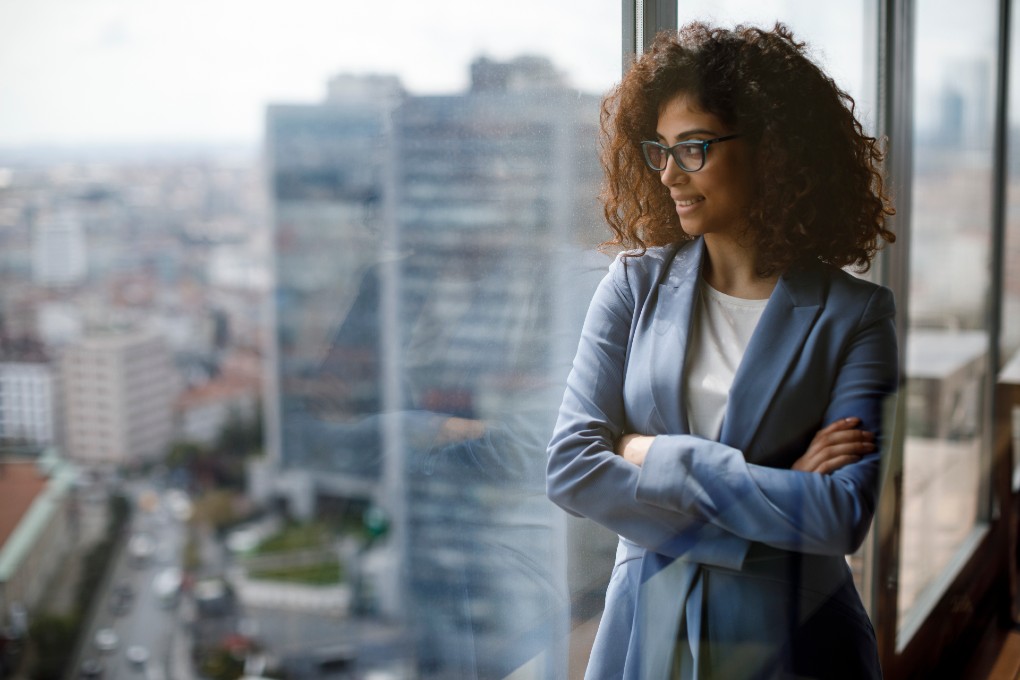 Photo d’une femme regardant par la fenêtre dans une tour à bureaux au centre-ville 