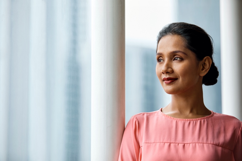 Photo of a woman gazing out a window, looking confident 