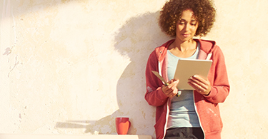 Young woman standing, holding a notebook 
