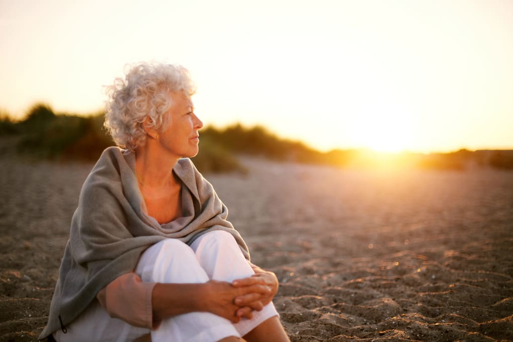 Photo of a retired woman sitting on the beach