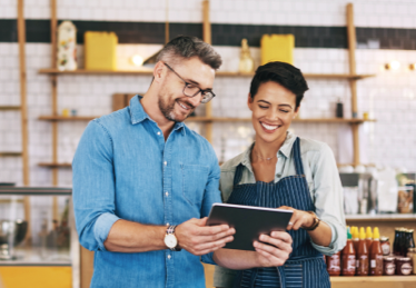 Photo of a woman in an apron and a man consulting a tablet in a restaurant kitchen in Florida