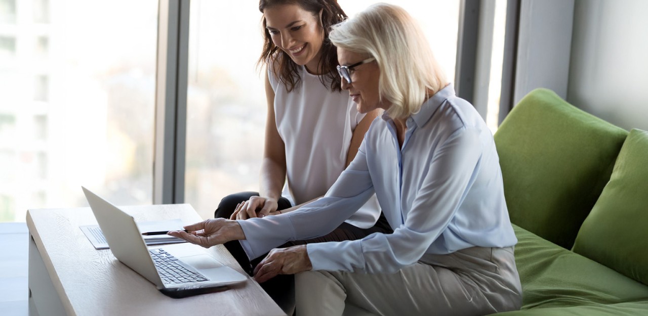 Photo of two people sitting on a chair looking at a computer