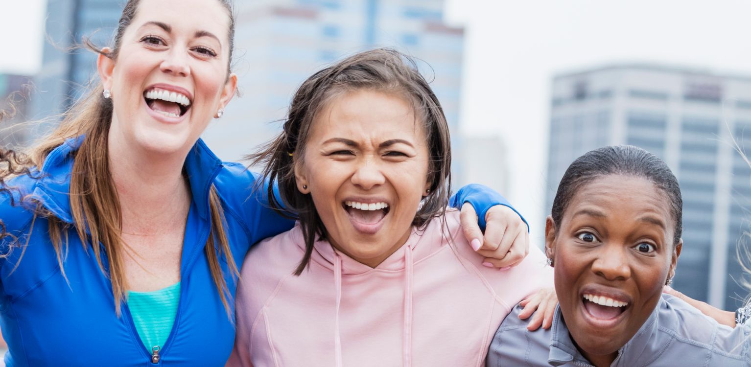 Photo of four people smiling with their arms around each other