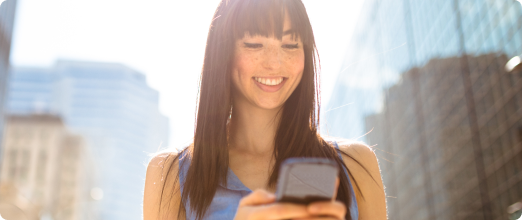 Photo of a woman looking at her phone while smiling 