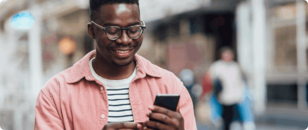 Photo of a young person looking at their phone and smiling 