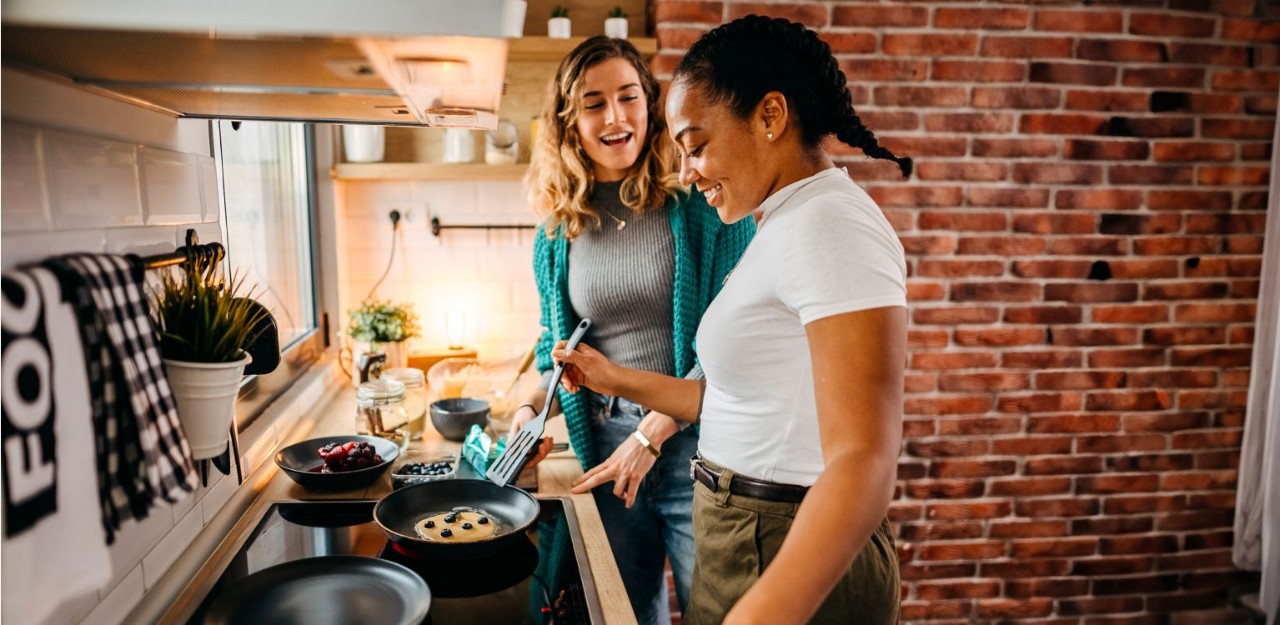 Photo of two people smiling while cooking  