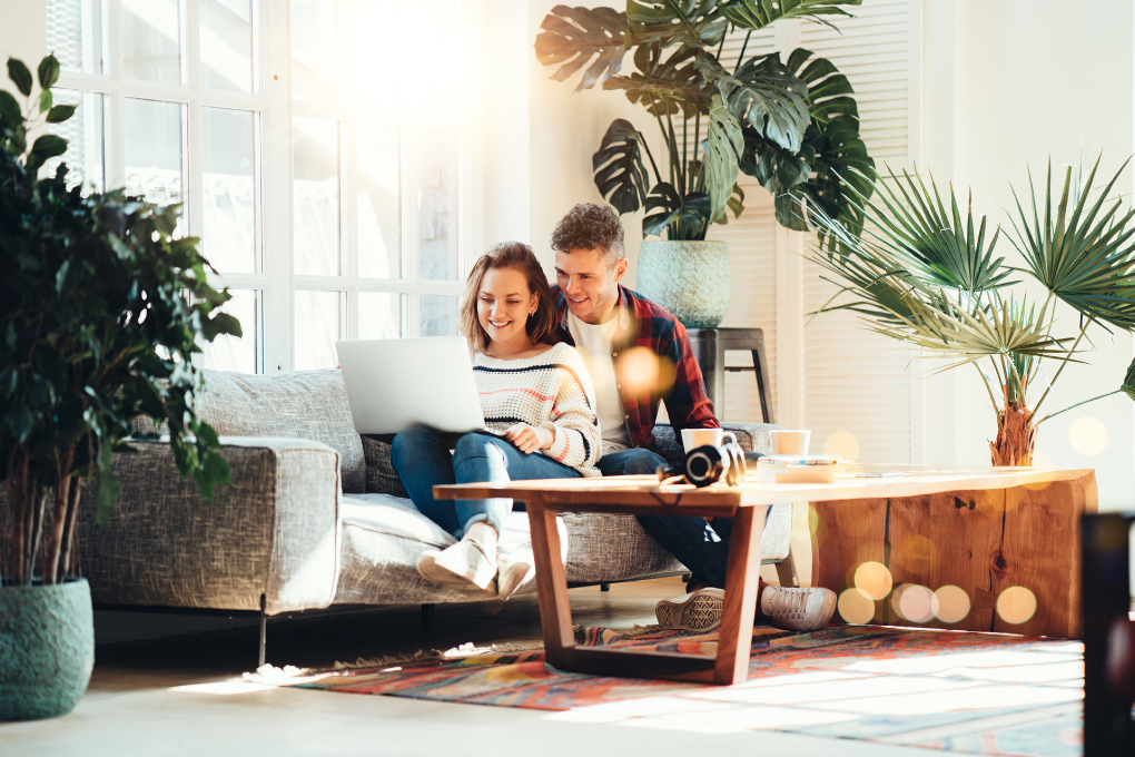 Photo of a couple sitting on their sofa and looking at a computer