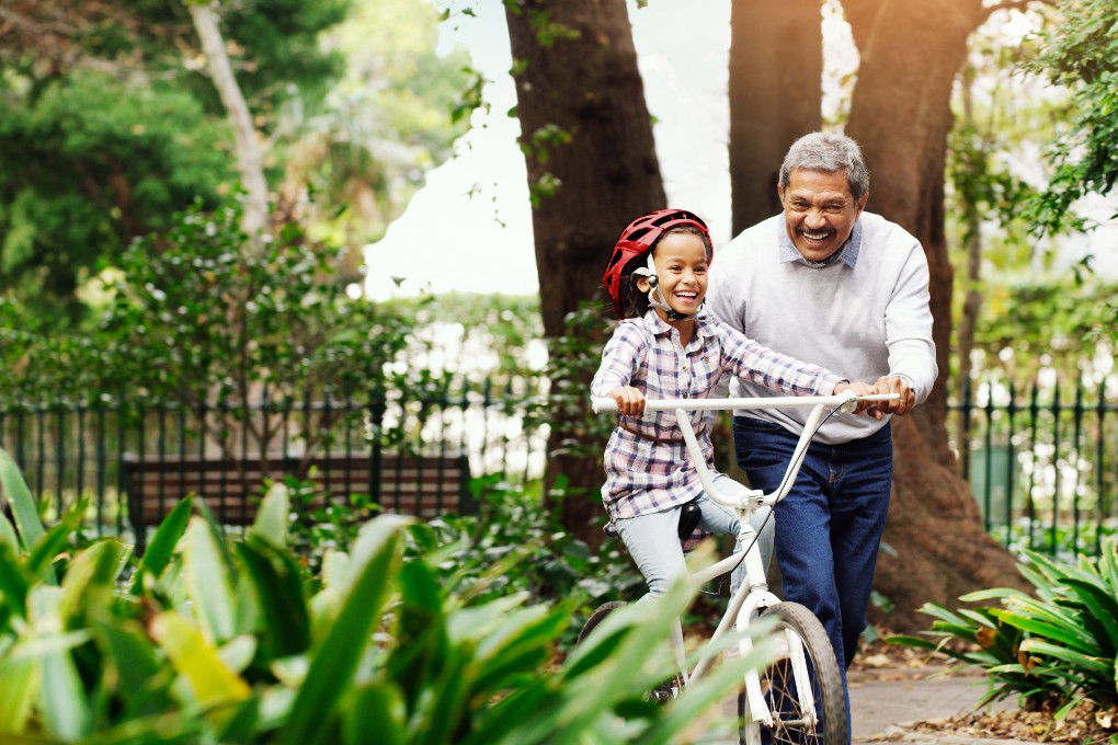 Photo of a grandfather teaching his granddaughter how to ride a bike
