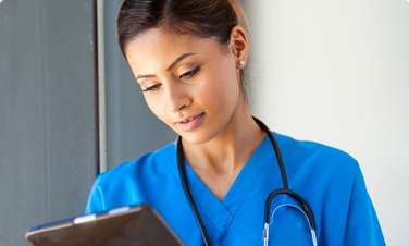 Photo of a young female nurse looking at a tablet.