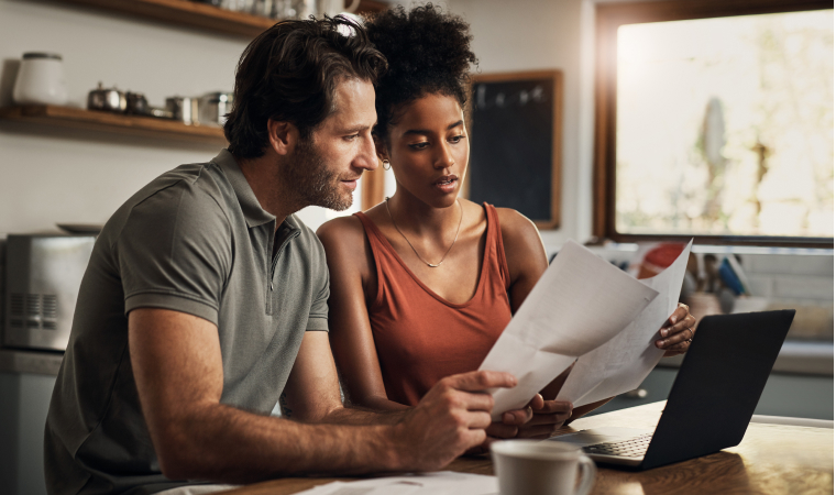Photo of a couple consulting documents in their kitchen