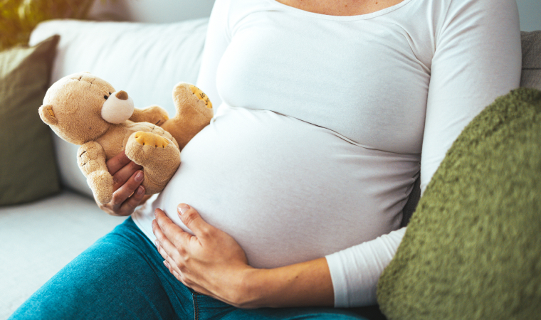 Photo of a pregnant woman holding a teddy bear
